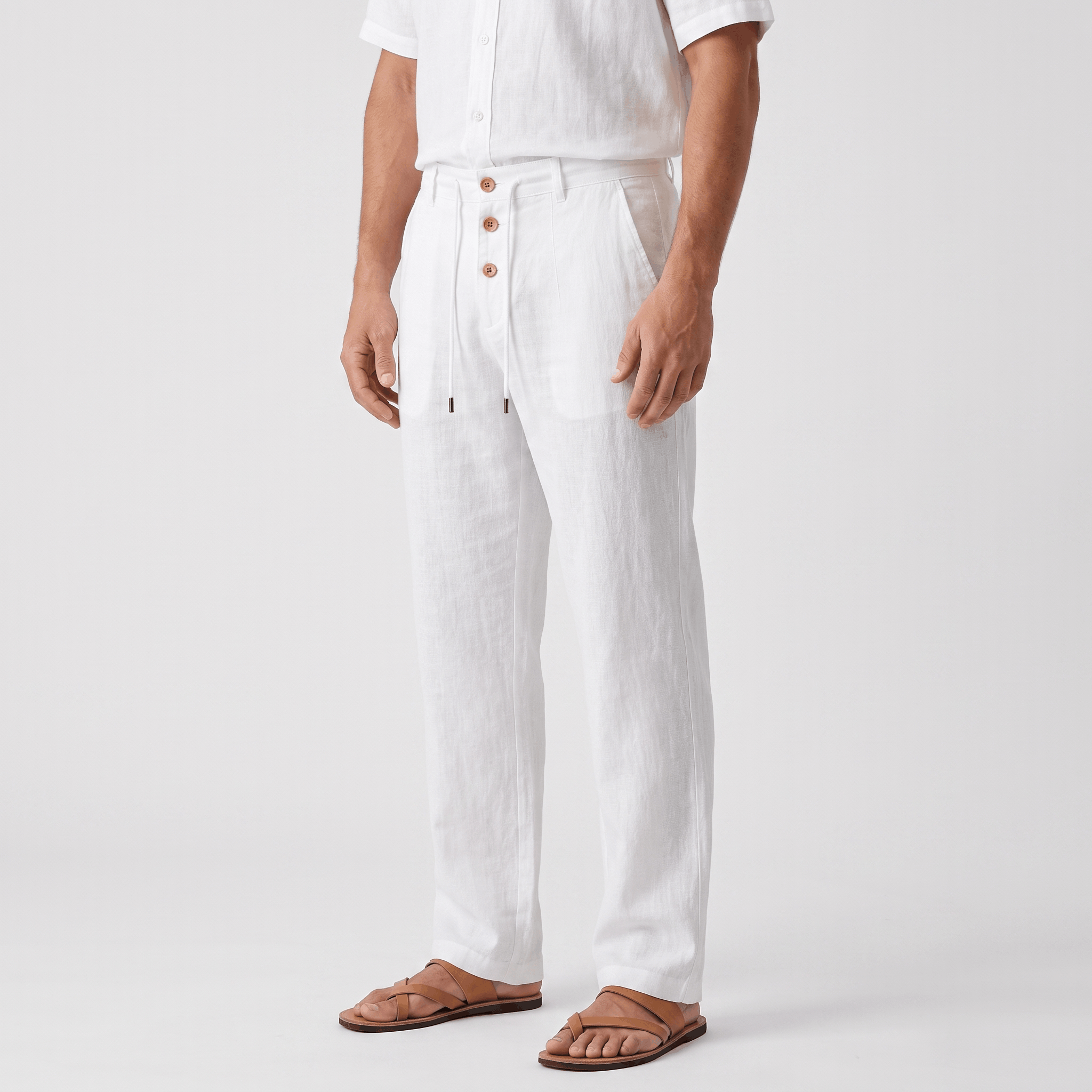 Side view of men's white linen drawstring pants featuring a relaxed straight-leg silhouette, button-front detail, and elastic waistband.