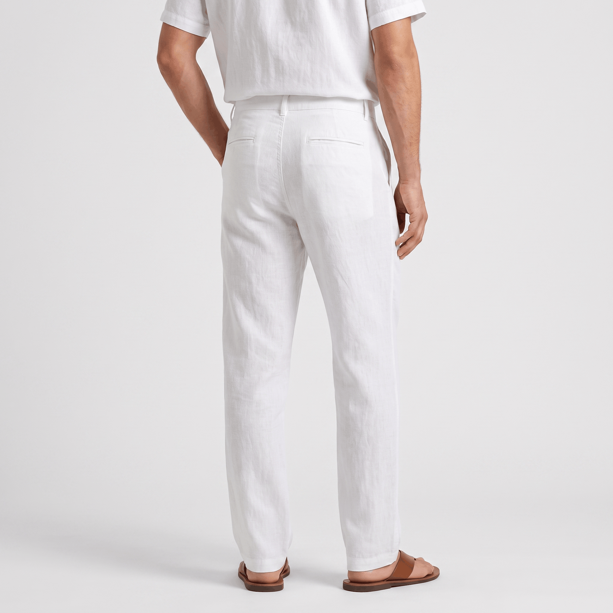 Back view of men's white linen drawstring pants with an elastic waistband, relaxed fit, and lightweight linen fabric.