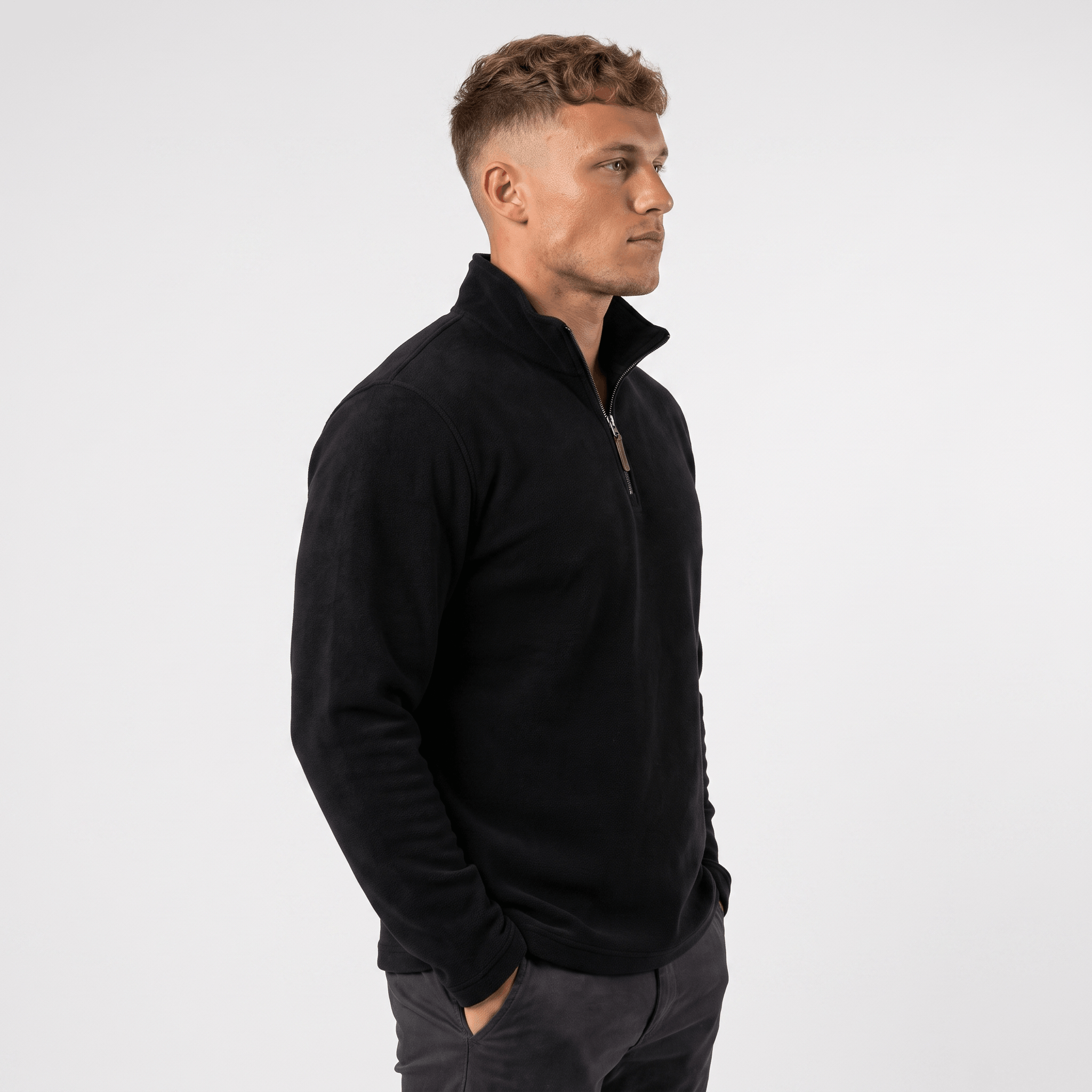 Side view of a man wearing a black quarter-zip sweater with a stand collar and classic silhouette.