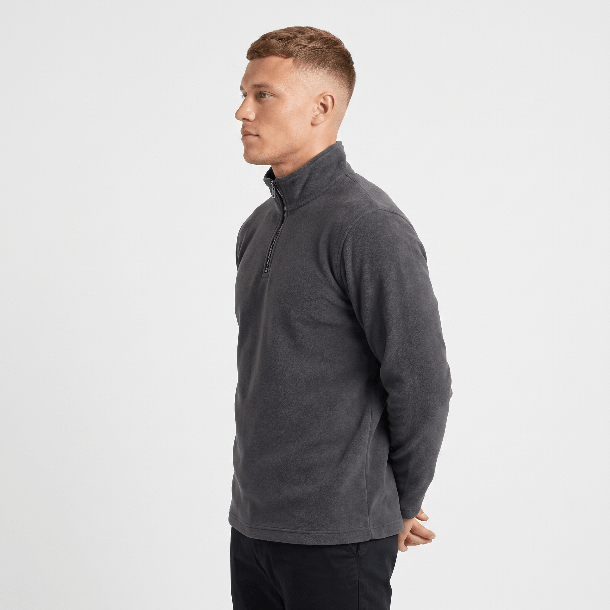 Side view of a man wearing a charcoal gray quarter-zip sweater with a stand collar and ribbed cuffs.