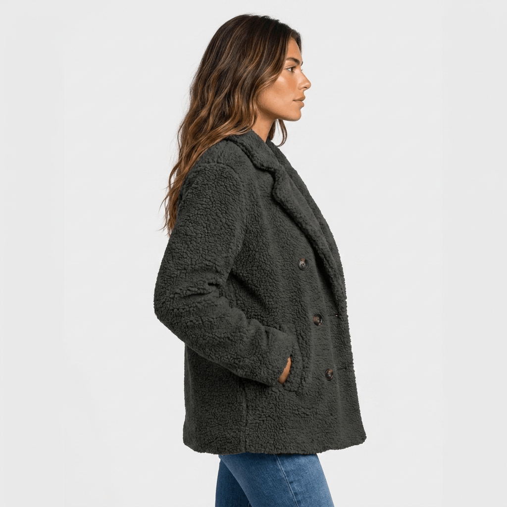 Side view of a woman wearing a dark gray textured double-breasted coat with wide lapels and side pockets.