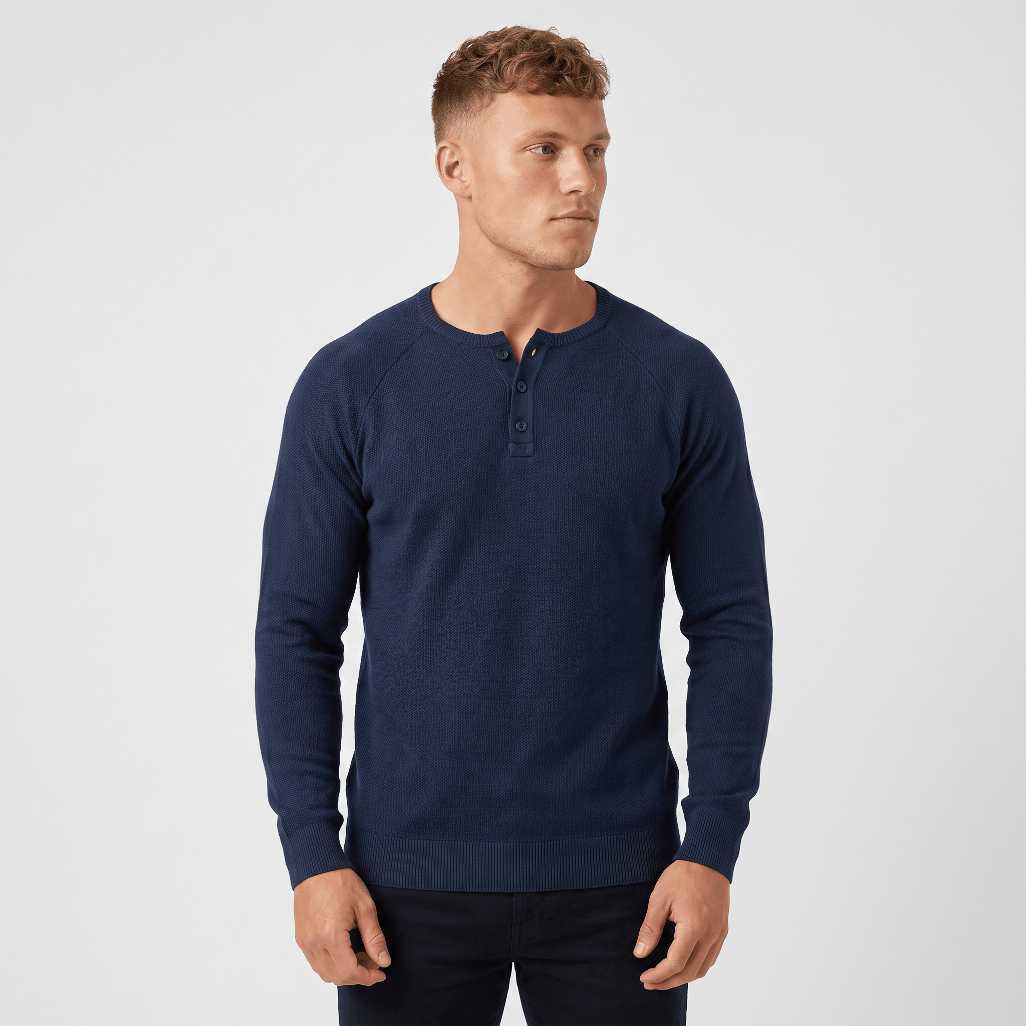 Man wearing a navy waffle knit Henley sweater with a three-button placket, long sleeves, and a modern slim fit.