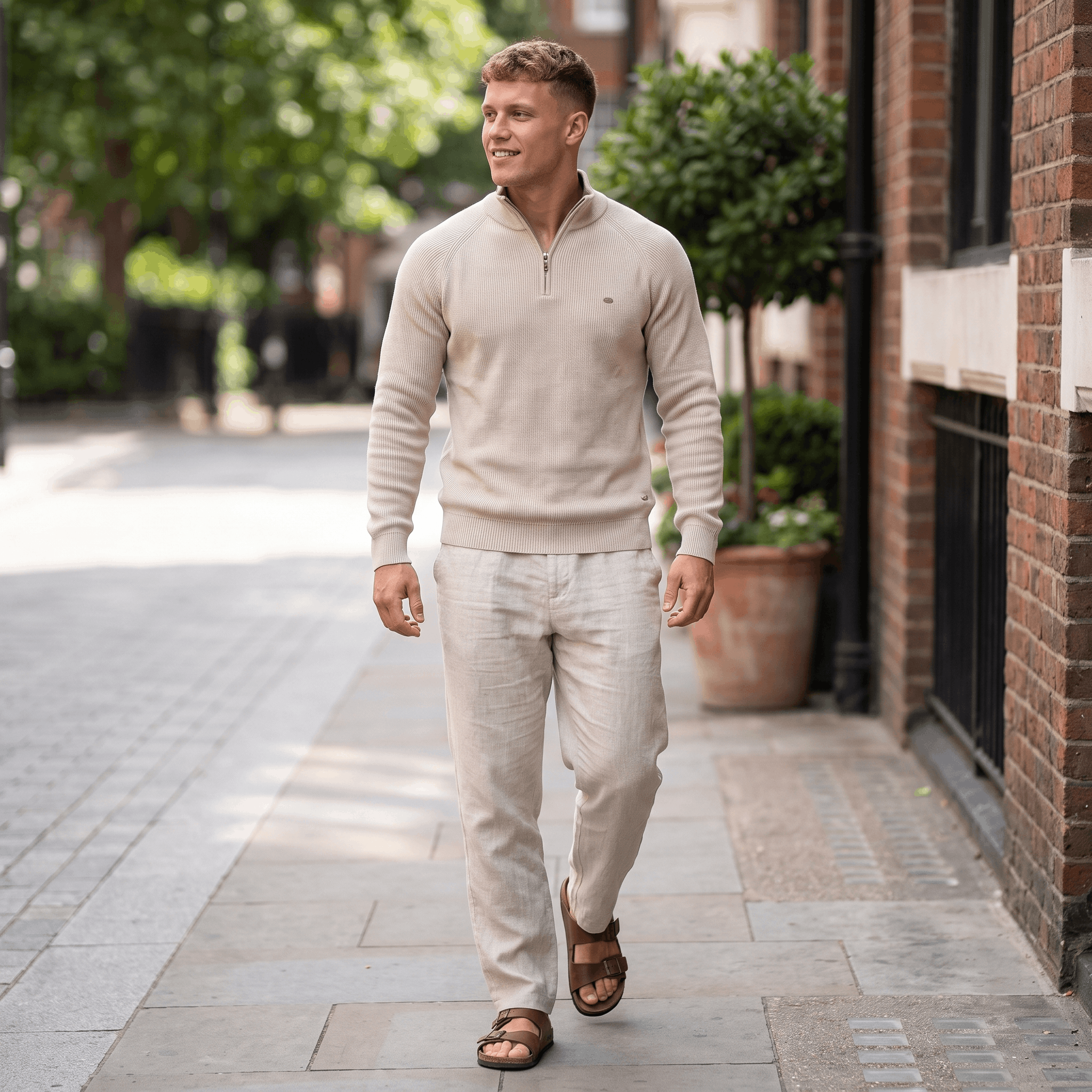 Man wearing a cream ribbed quarter-zip knit sweater paired with light-colored trousers while walking in an urban street setting.