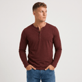 Man wearing a burgundy long-sleeve Henley shirt with a three-button placket, crew neckline, and modern slim fit.