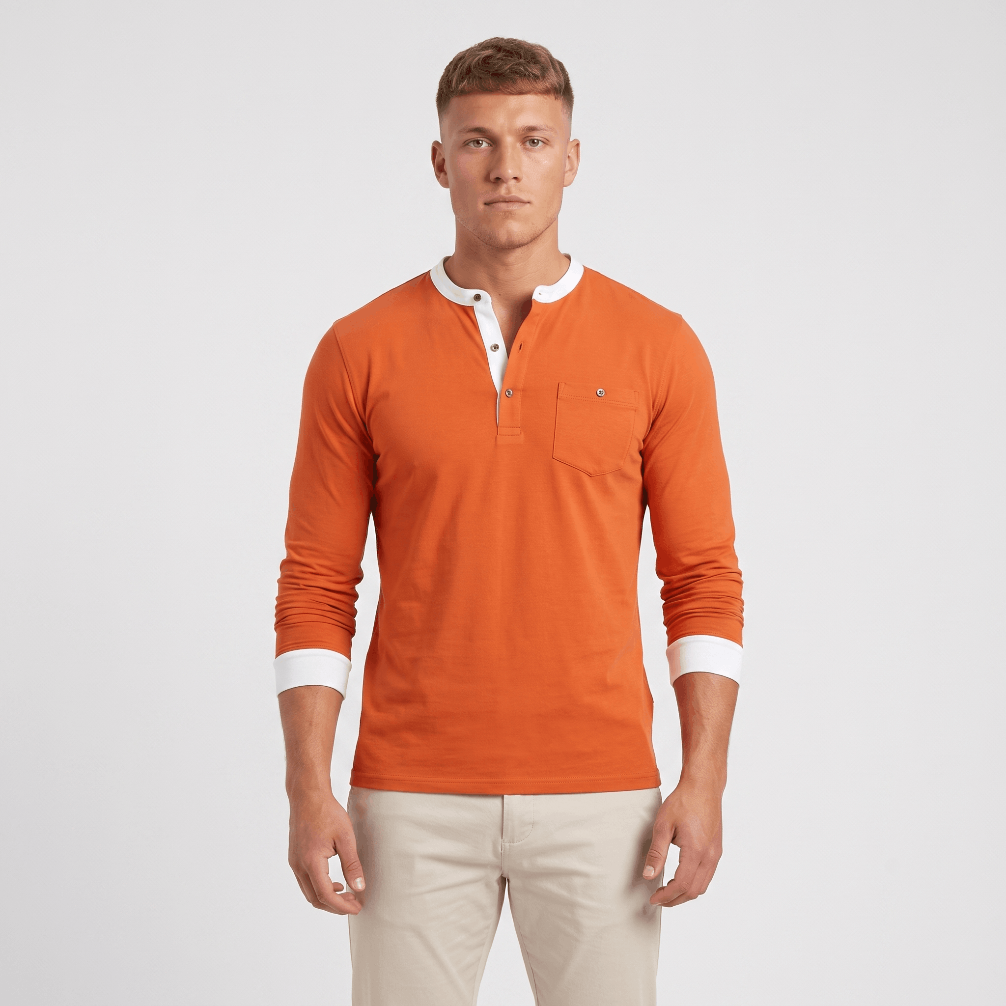 Man wearing an orange long-sleeve Henley sweater with a white contrast placket and cuffs, three-button neckline, chest logo, and modern slim fit.