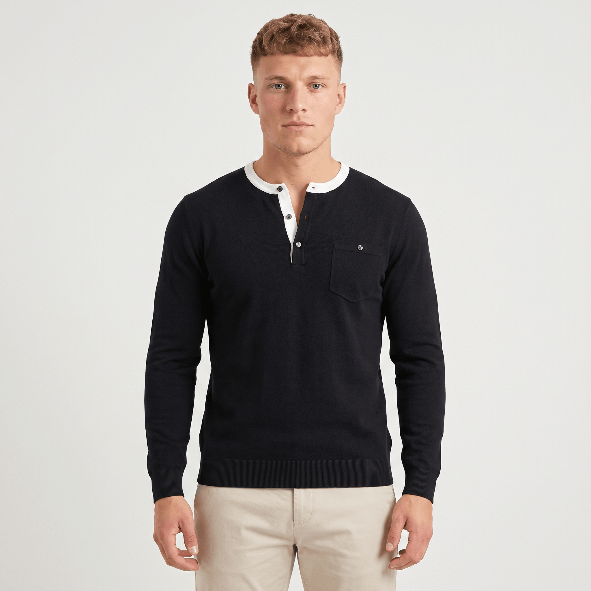 Man wearing a black long-sleeve Henley sweater with a white contrast placket and collar trim, three-button neckline, chest logo, and modern slim fit.