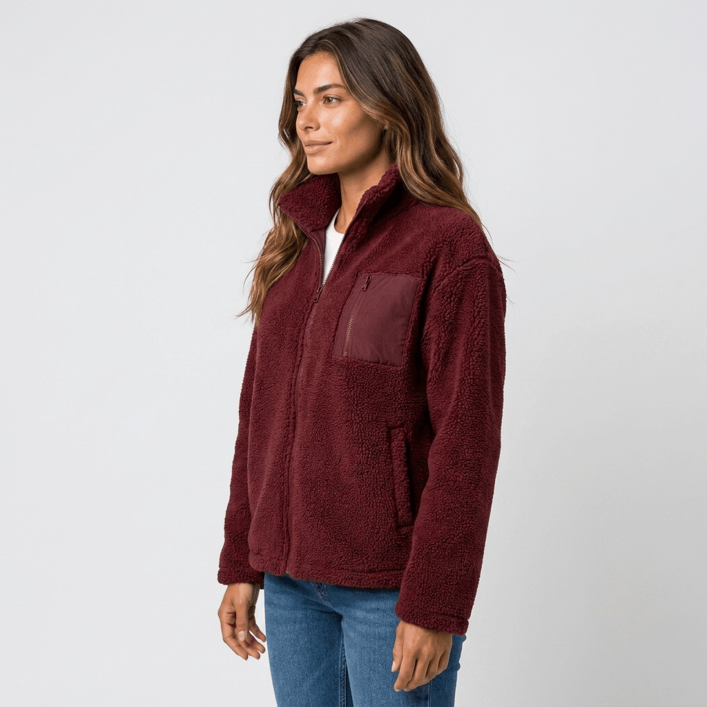 Side view of a woman wearing a burgundy textured fleece jacket with a stand collar, front zip closure, and relaxed silhouette.
