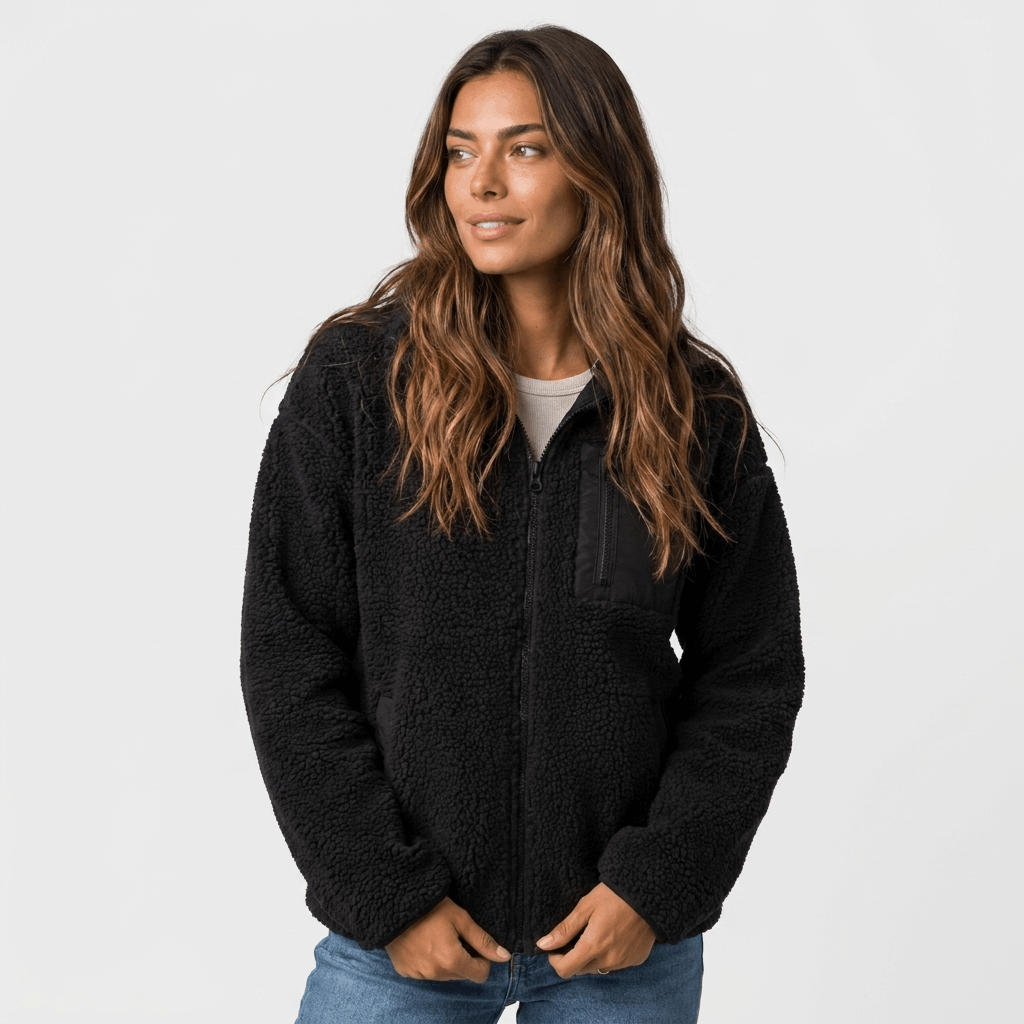 Woman wearing a black textured fleece jacket with a stand collar, front zip closure, and relaxed fit over a white top and blue jeans.