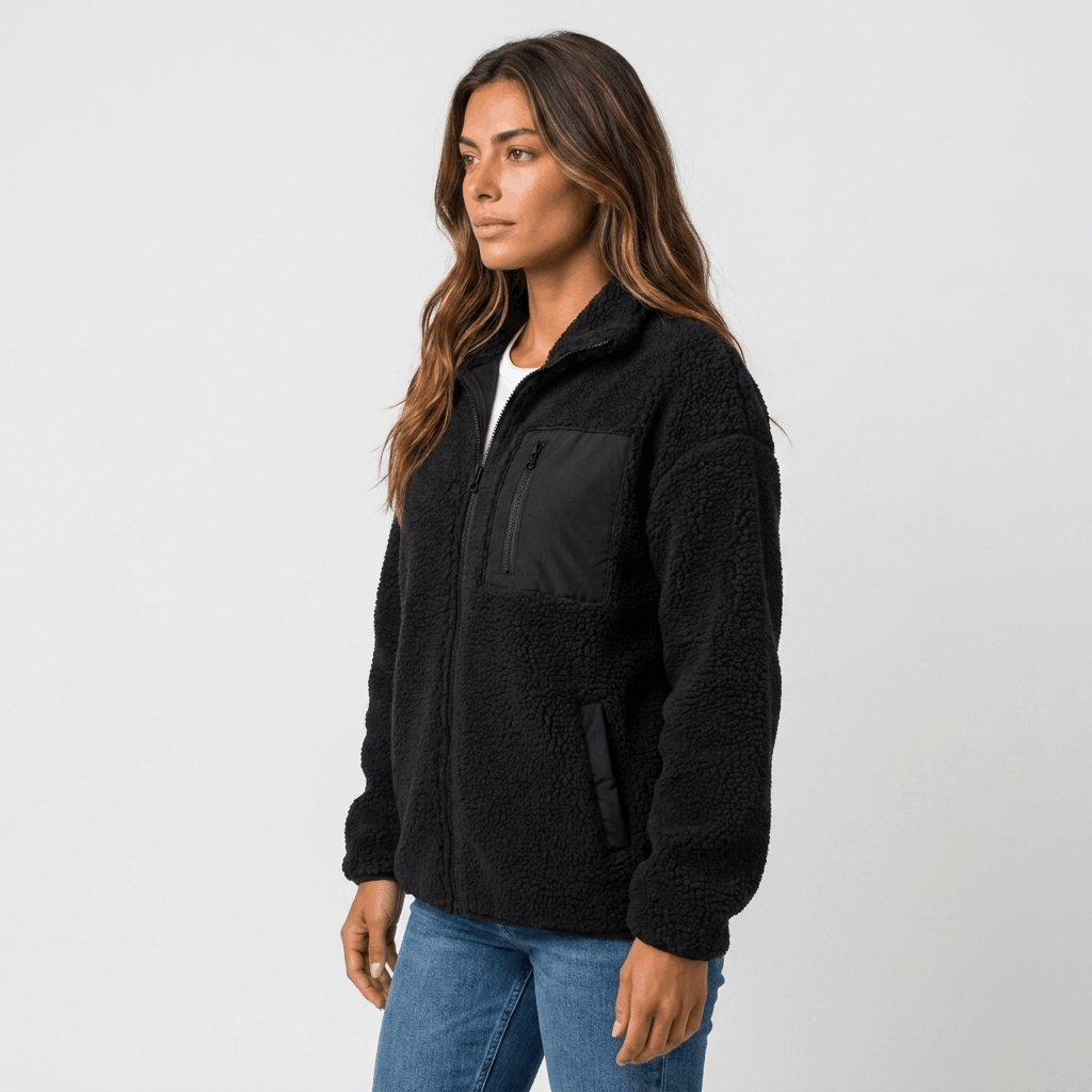 Side view of a woman wearing a black textured fleece jacket with a stand collar, front zip closure, and relaxed silhouette.