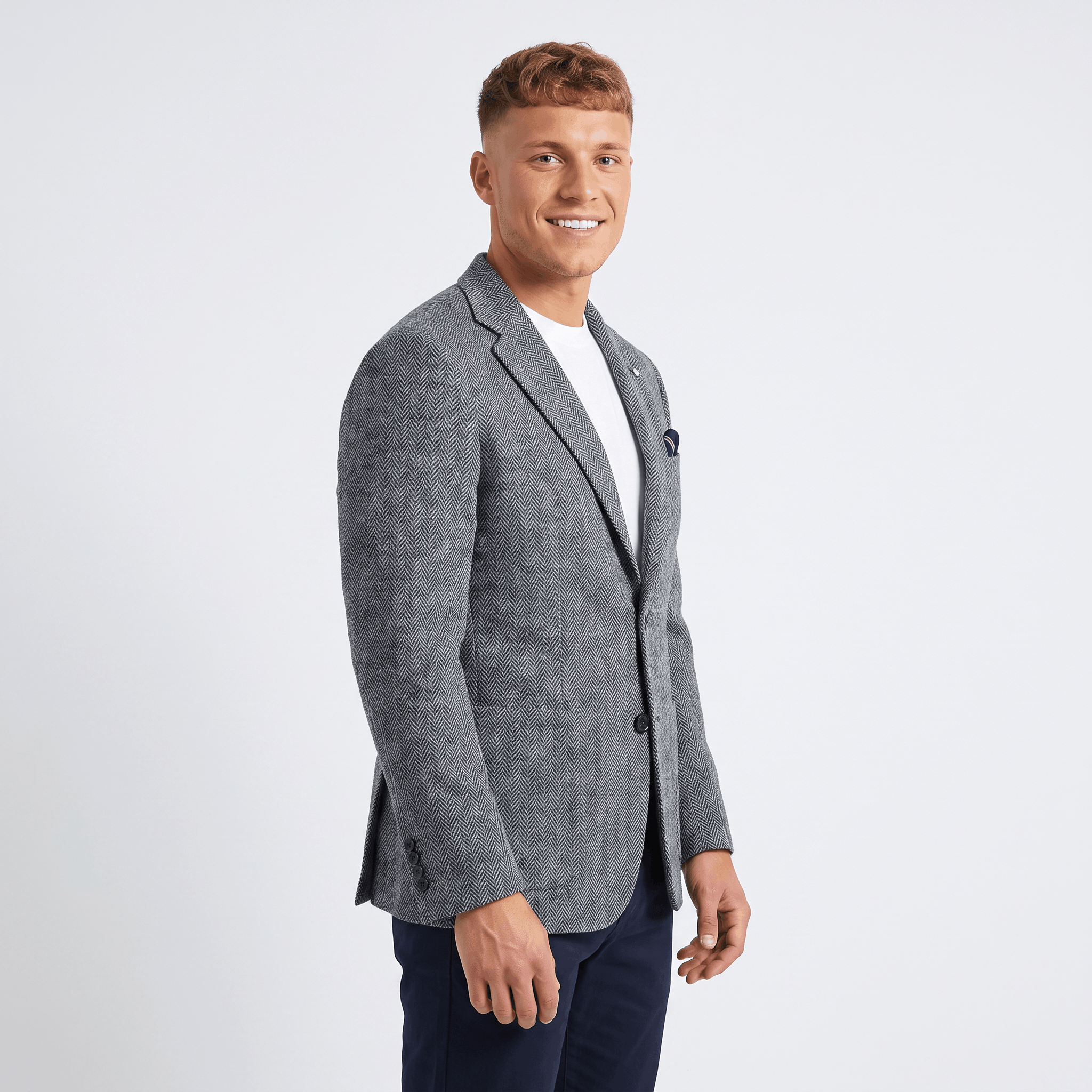 Side view of a man wearing a gray tweed blazer with a notched lapel, two-button closure, and tailored silhouette.