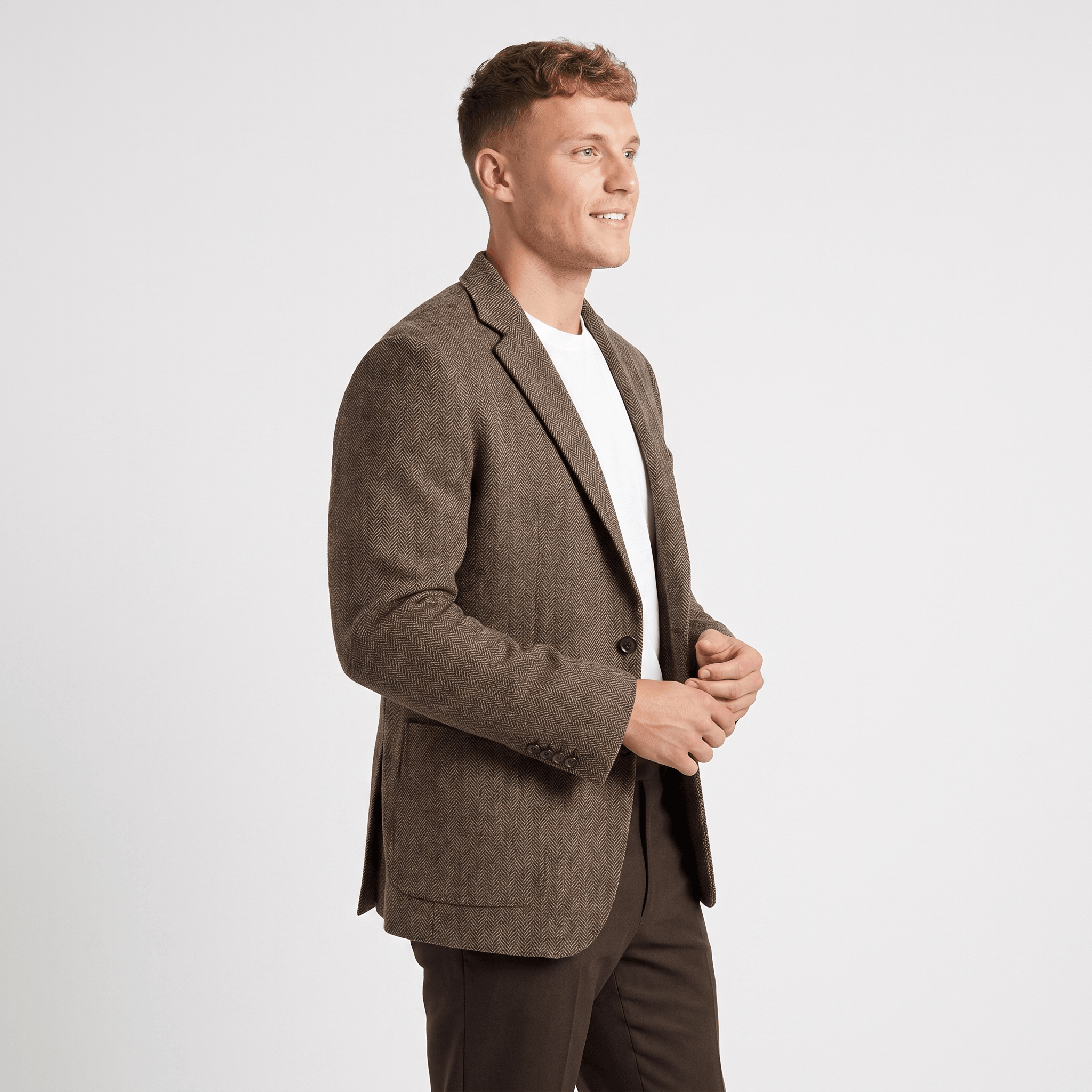 Side view of a man wearing a brown tweed blazer with a notched lapel, button closure, and tailored silhouette.