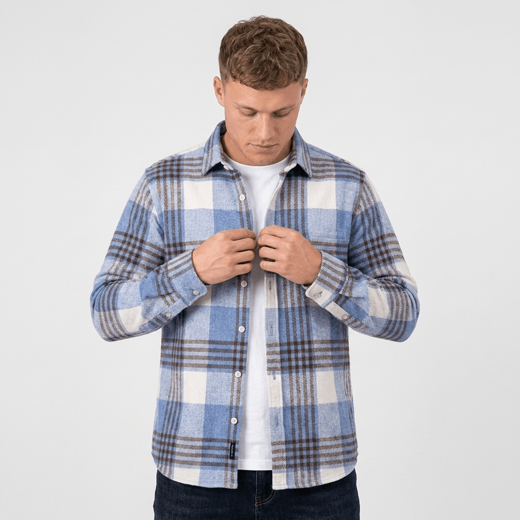 Man wearing a blue and white plaid overshirt jacket while adjusting the button-front closure.