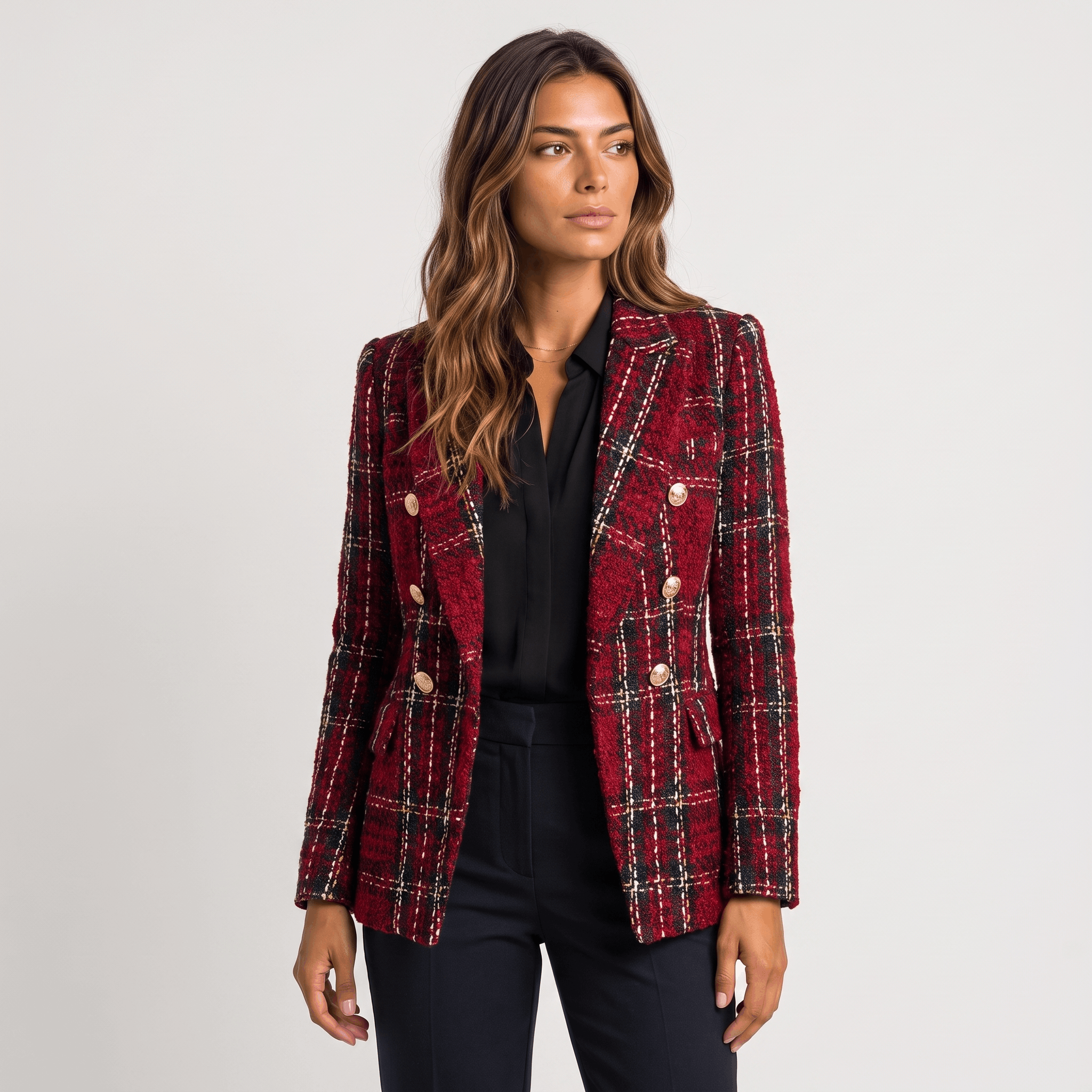 Woman wearing a red plaid tweed blazer with gold-tone buttons, notched lapels, and tailored silhouette over a black top.