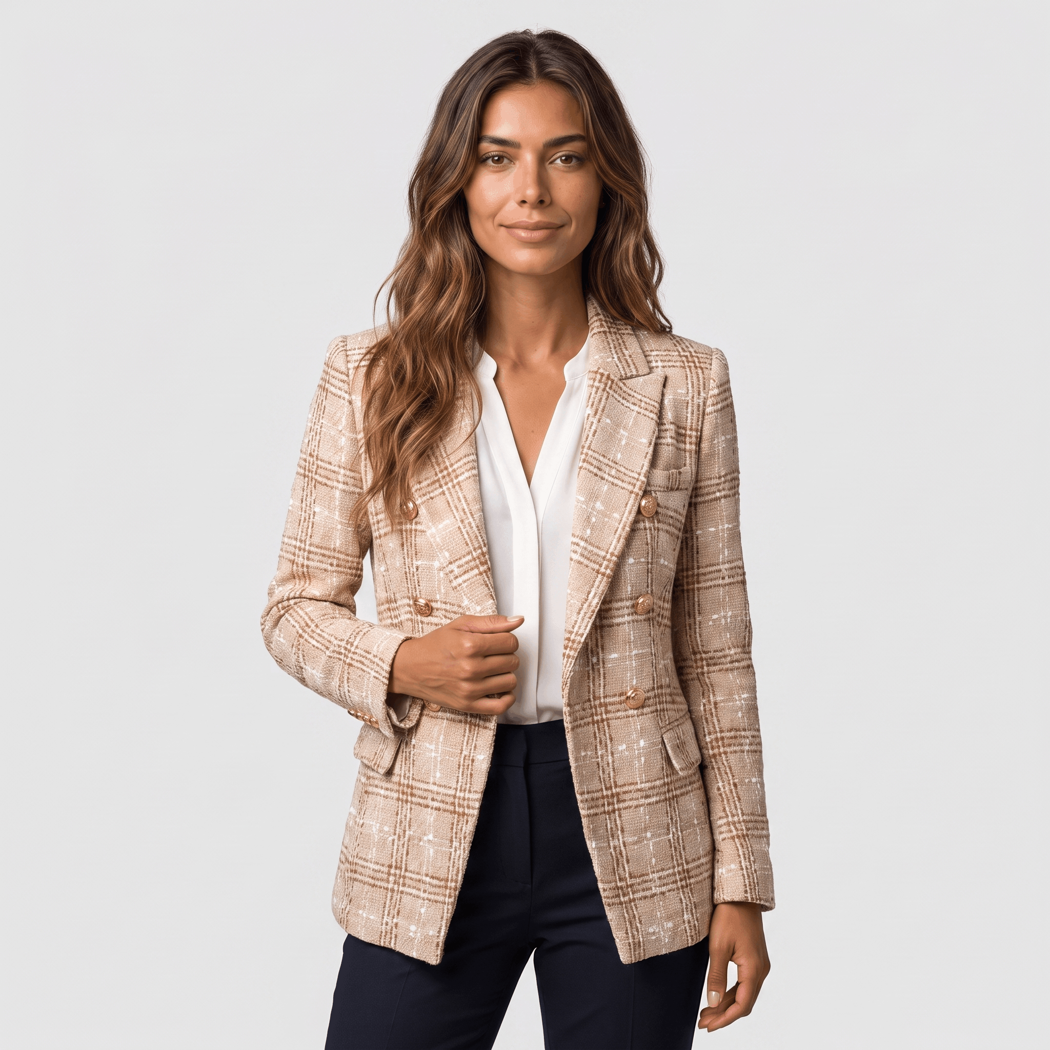 Woman wearing a beige plaid tweed blazer with gold-tone buttons, notched lapels, flap pockets, and tailored fit over a white blouse.
