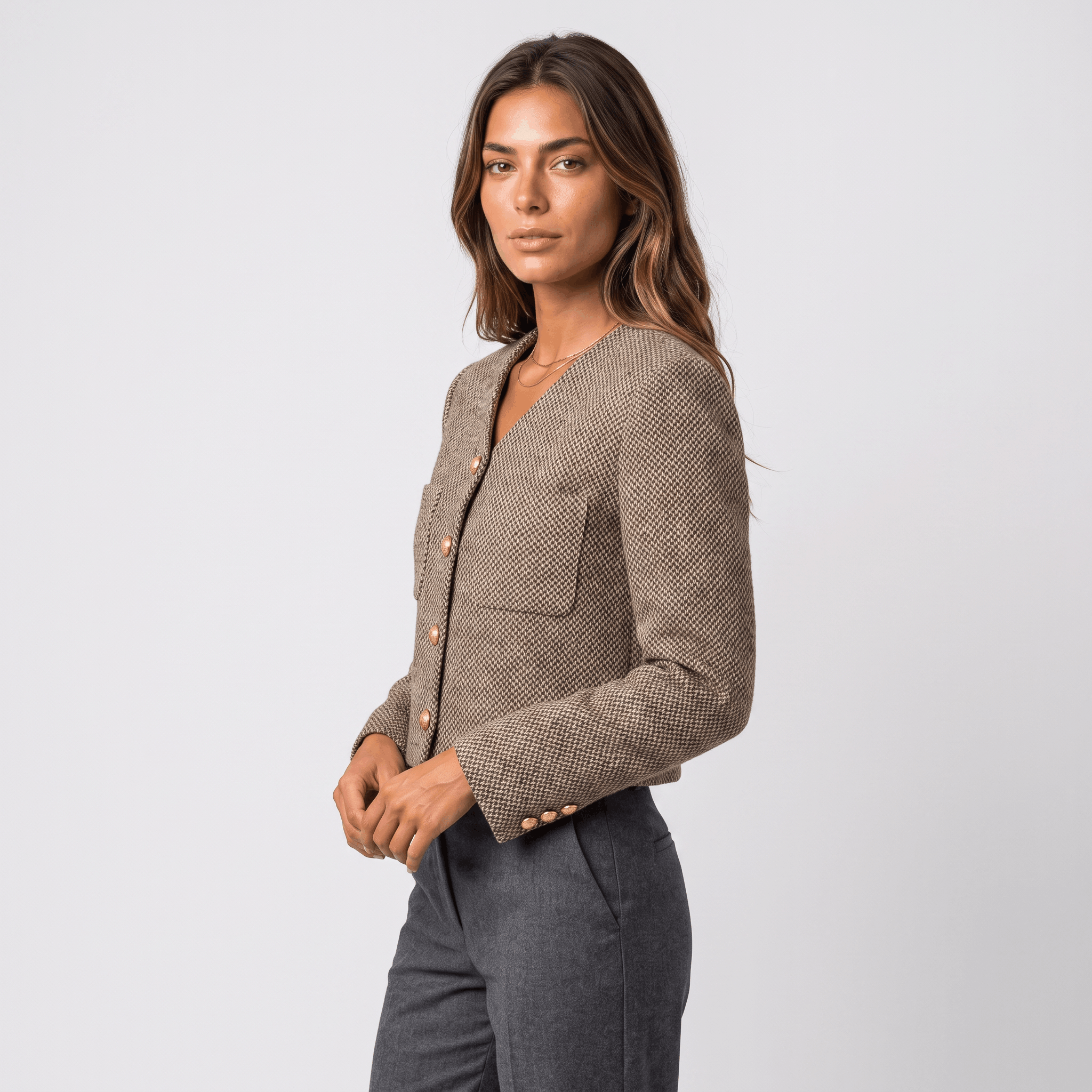 Side view of a woman wearing a brown textured tweed blazer with gold-tone buttons and a fitted silhouette.