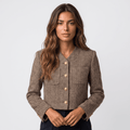 Woman wearing a brown textured tweed blazer with gold-tone button closure, round neckline, long sleeves, and tailored silhouette.