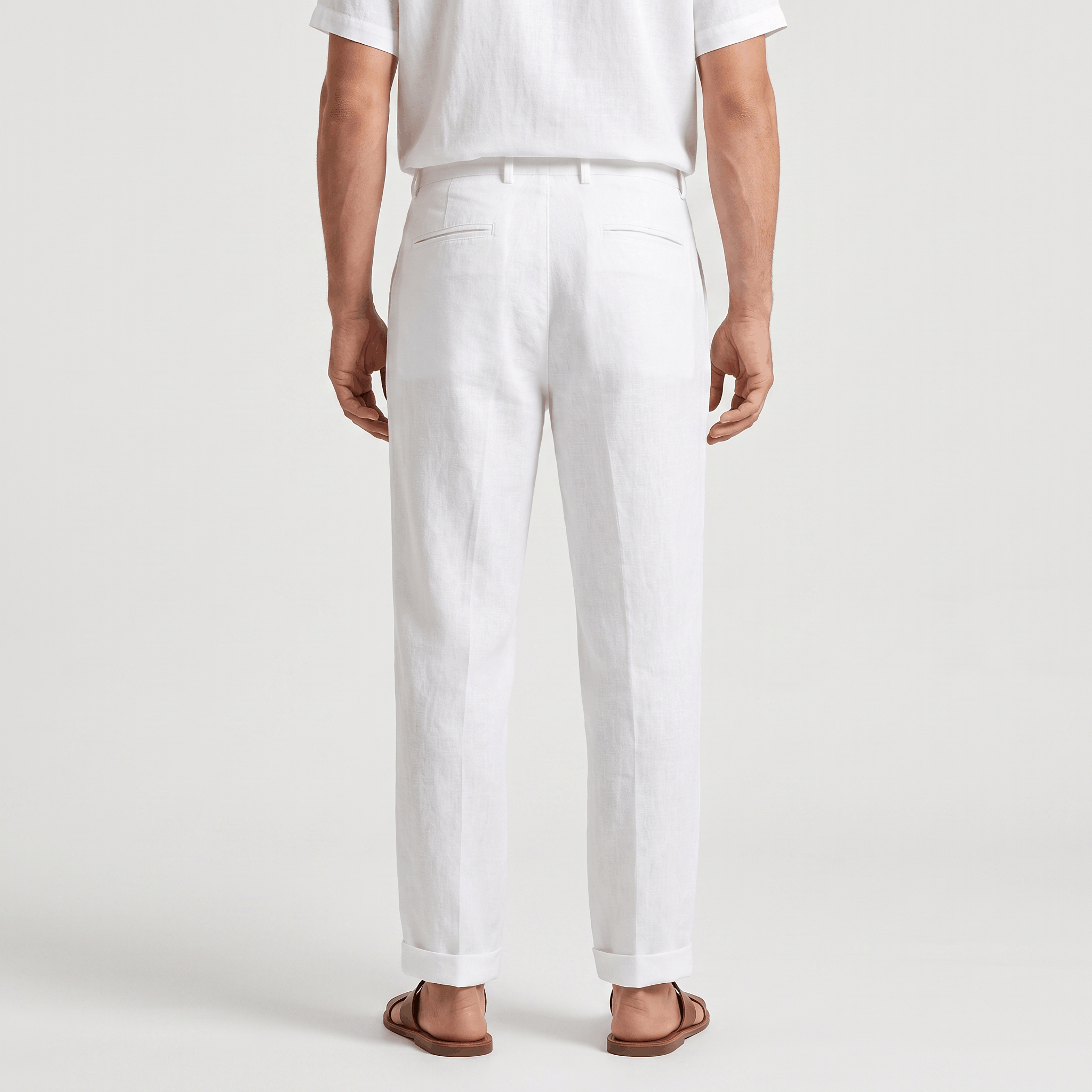 Back view of men's white linen pants with belt loops, a tailored fit, and lightweight linen construction.
