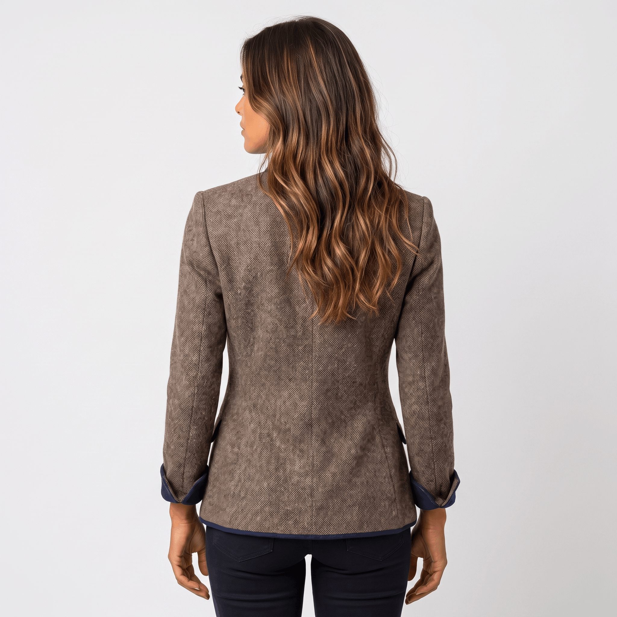 Back view of a woman wearing a brown tweed blazer with contrasting navy trim and a tailored silhouette.