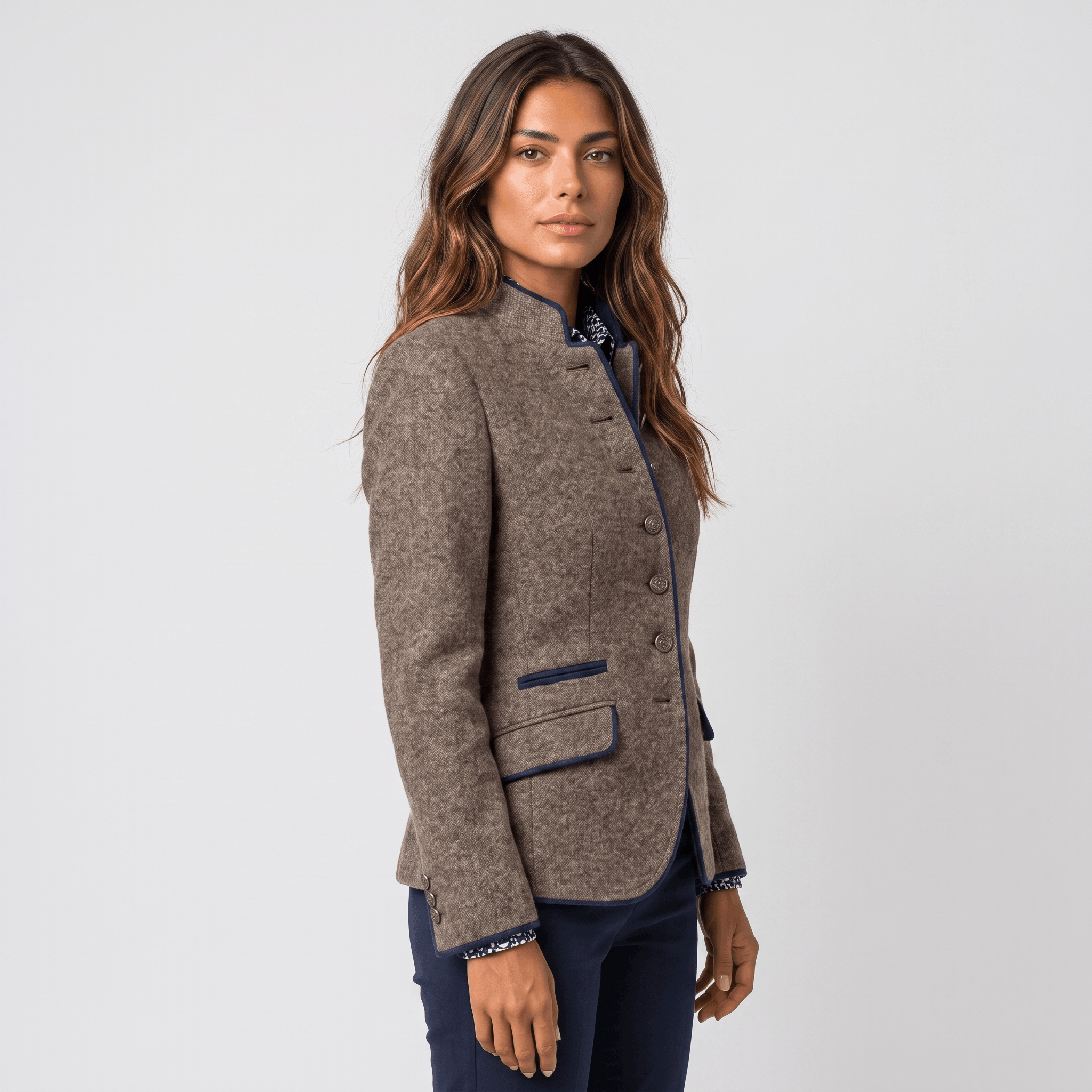 Side view of a woman wearing a brown tweed blazer with navy-trimmed lapels, button closure, and tailored fit.