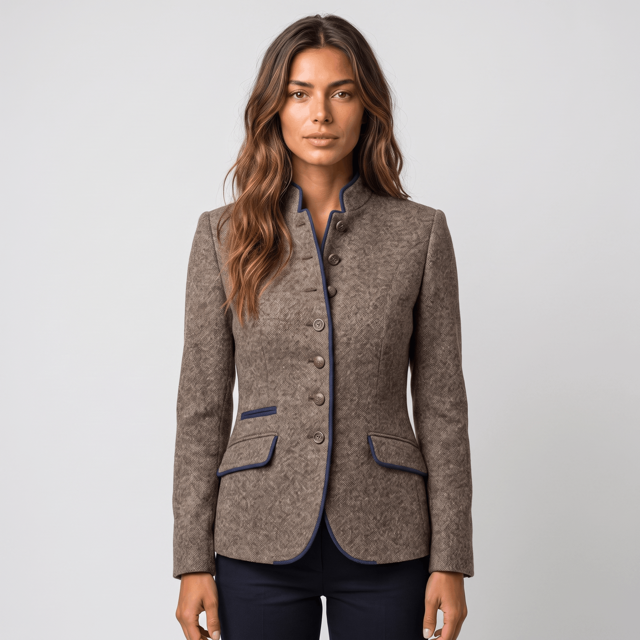Front view of a woman wearing a brown tweed blazer with navy trim, button closure, flap pockets, and fitted silhouette.