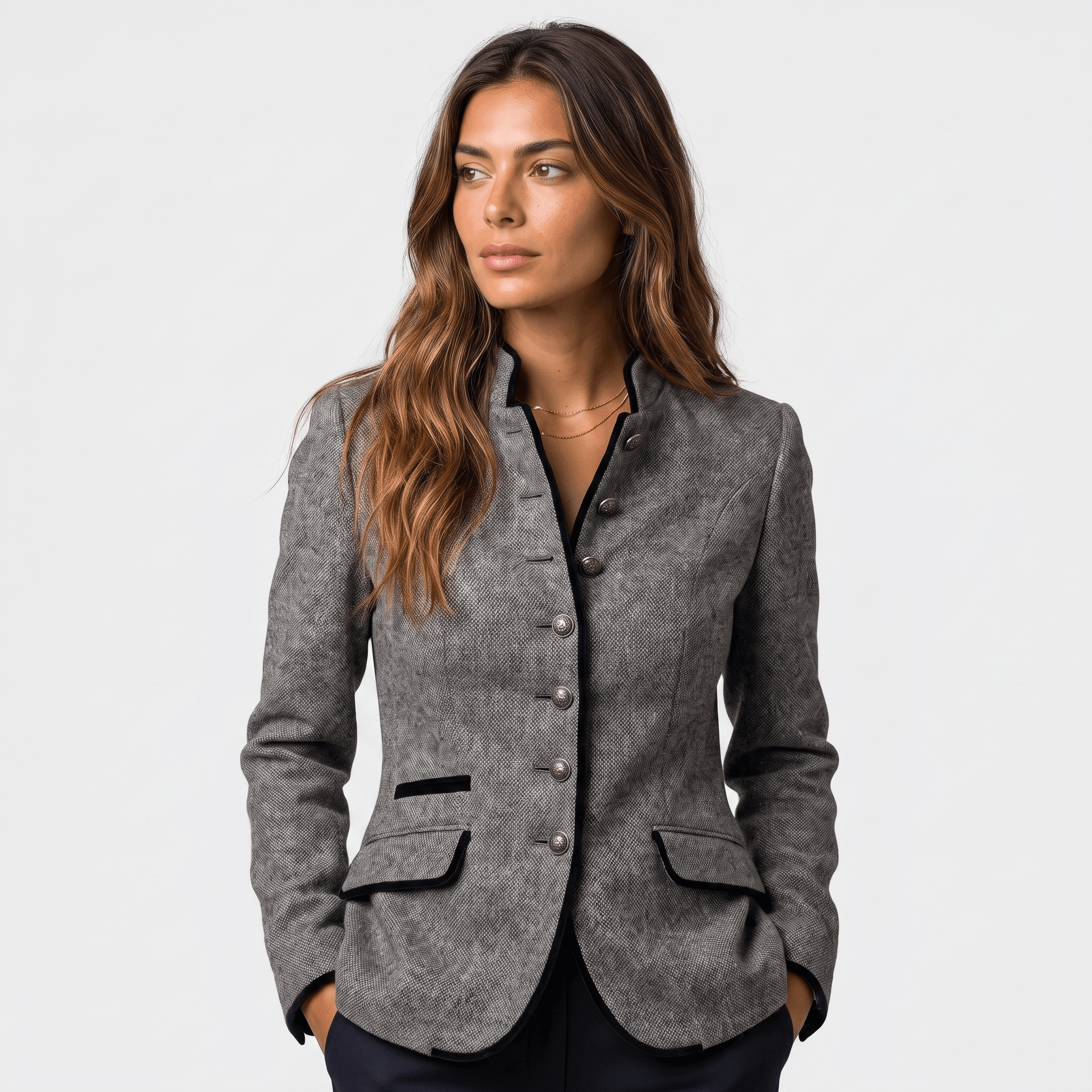 Woman wearing a gray tweed blazer with contrasting dark trim, button-front closure, notched lapel, and flap pockets.