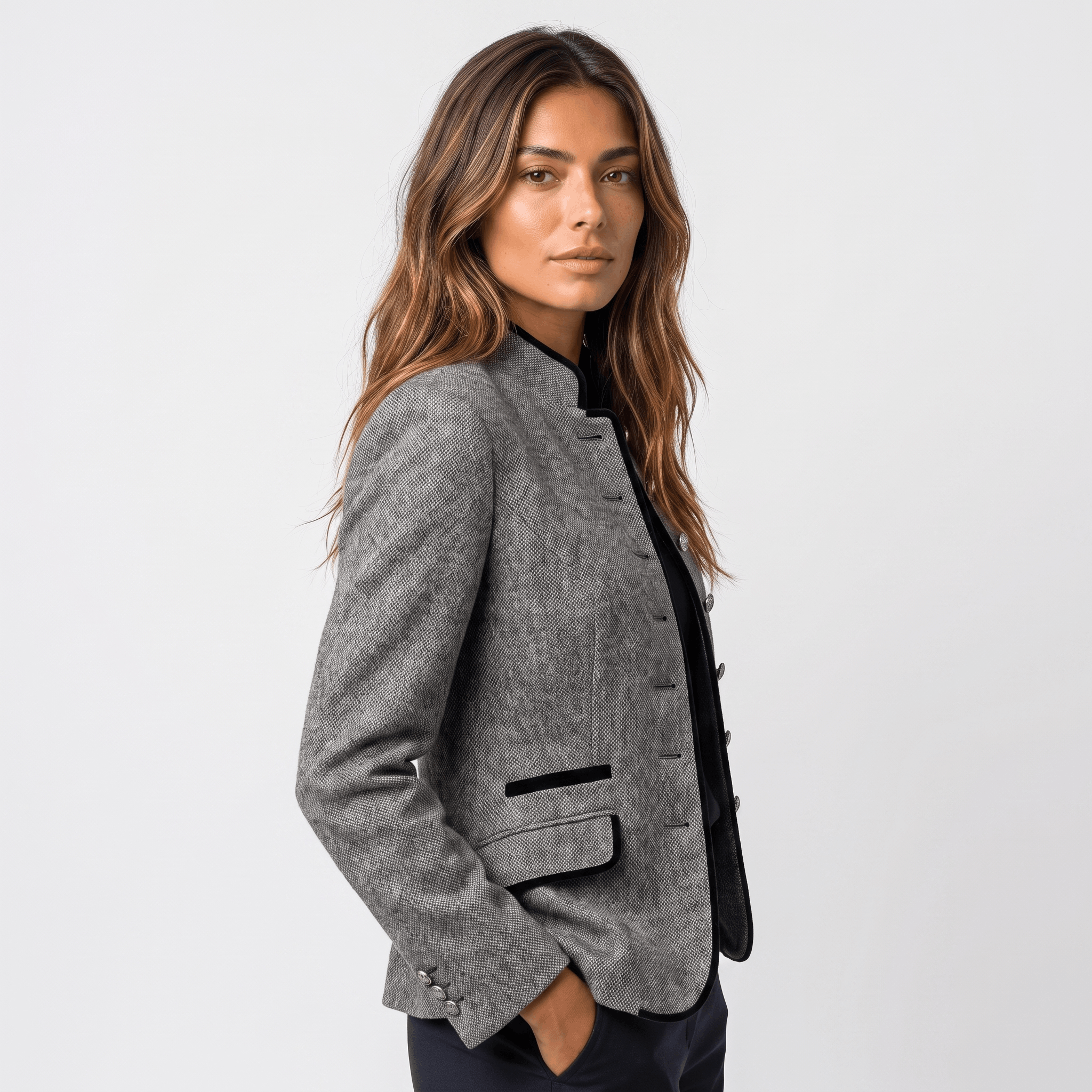 Side view of a woman wearing a gray tweed blazer with dark contrasting trim and a tailored silhouette.