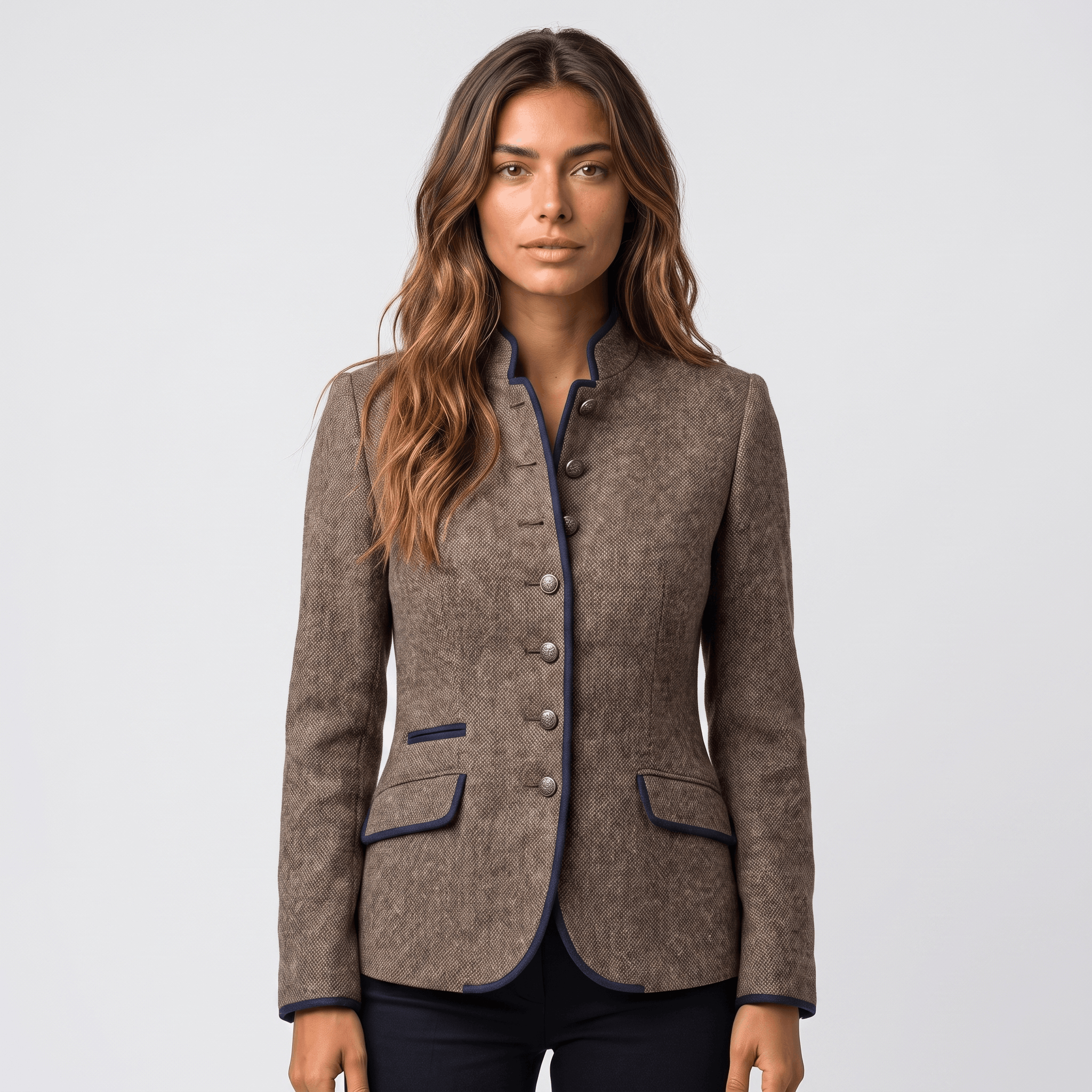 Woman wearing a brown tweed blazer with contrasting navy trim, button-front closure, notched collar, and flap pockets.