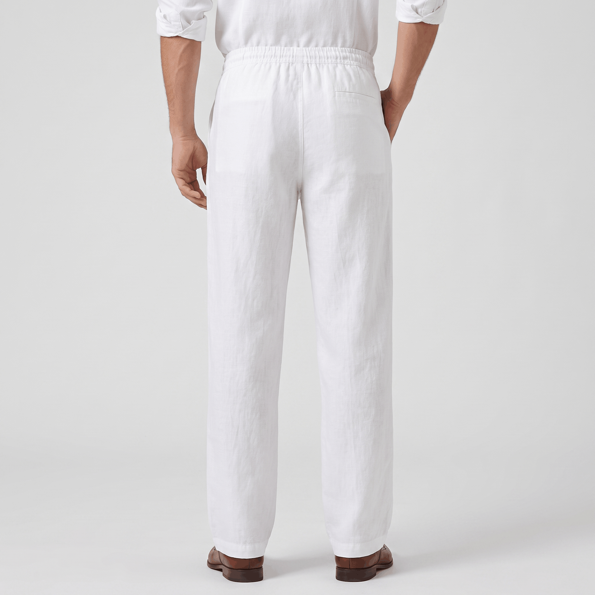 Back view of men's white linen drawstring pants with an elastic waistband, relaxed fit, and lightweight linen construction.