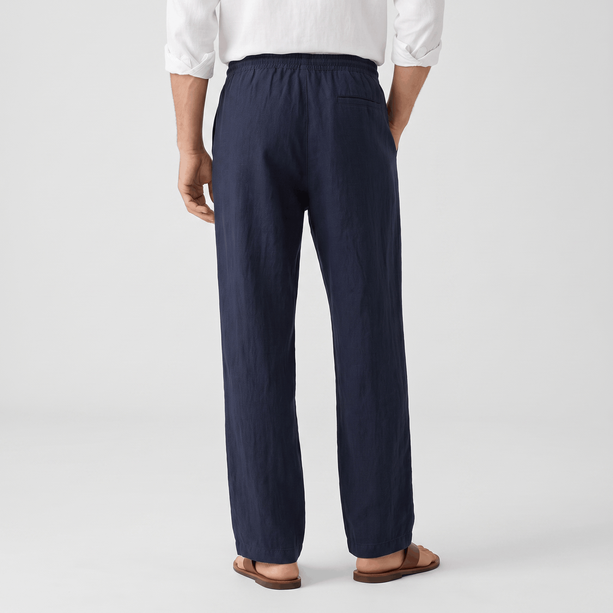 Back view of men's navy linen drawstring pants with an elastic waistband and breathable linen construction.