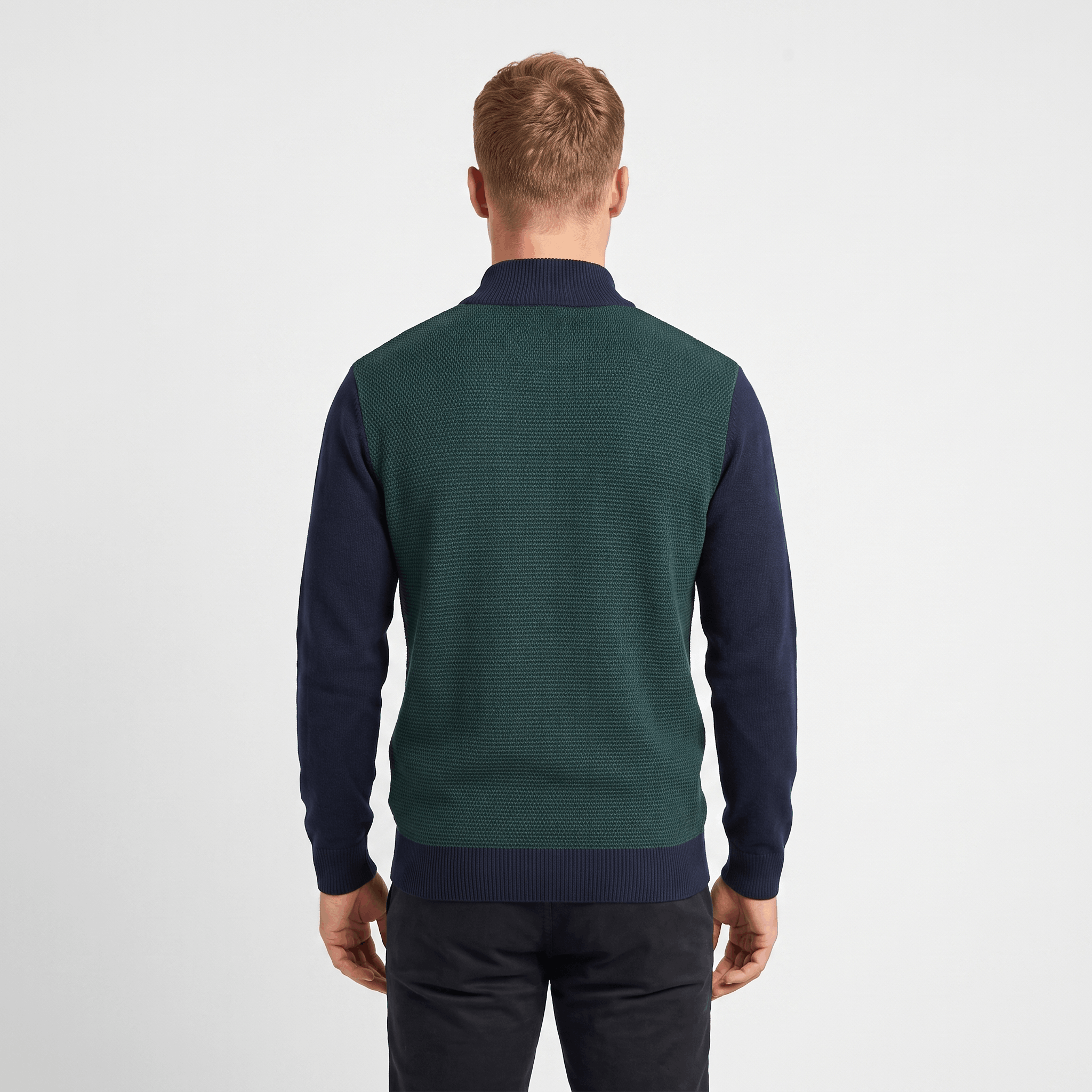 Back view of a men's green and navy color block quarter-zip knit sweater with ribbed texture and stand collar.