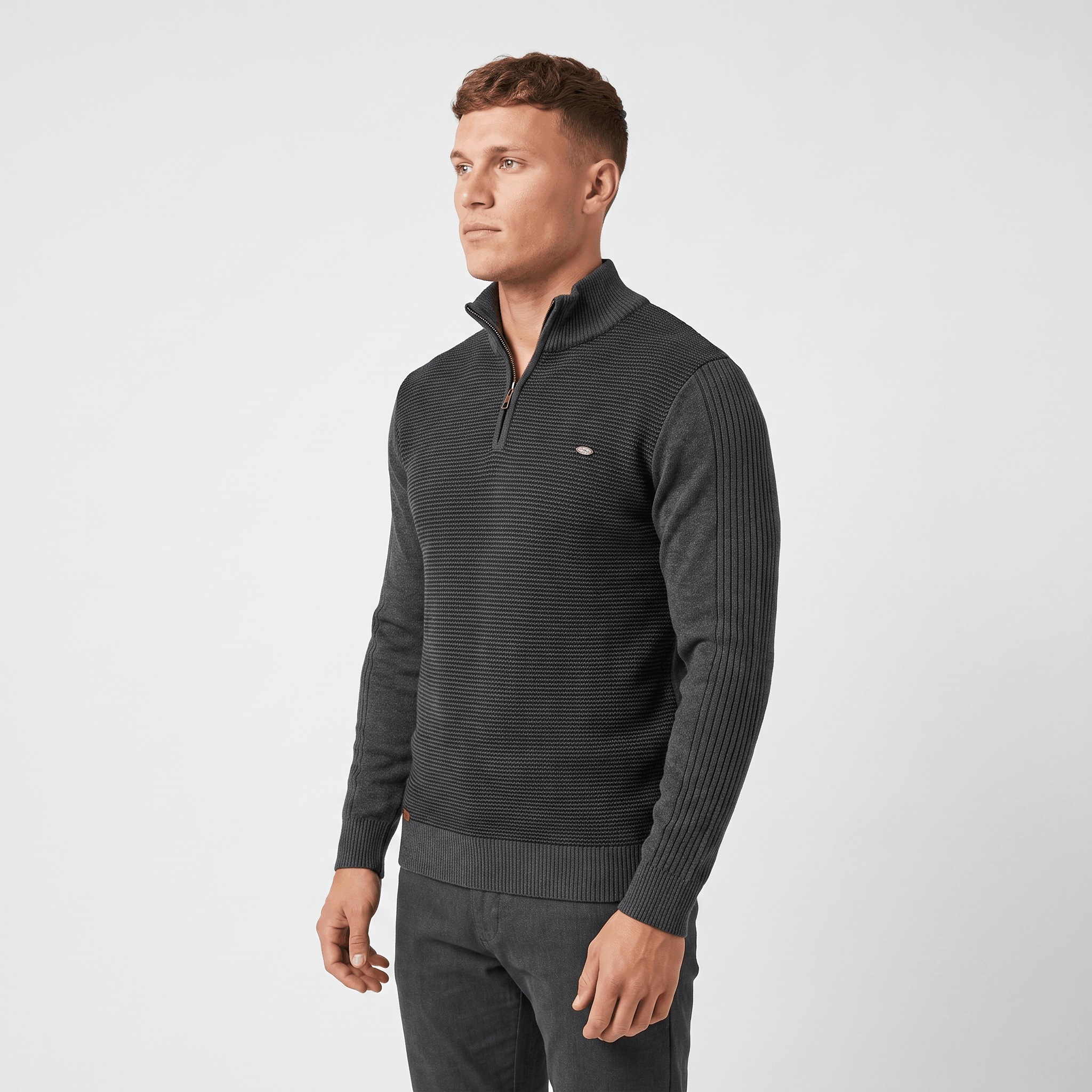 Side view of a man wearing a charcoal ribbed quarter-zip sweater with a stand collar and long sleeves.