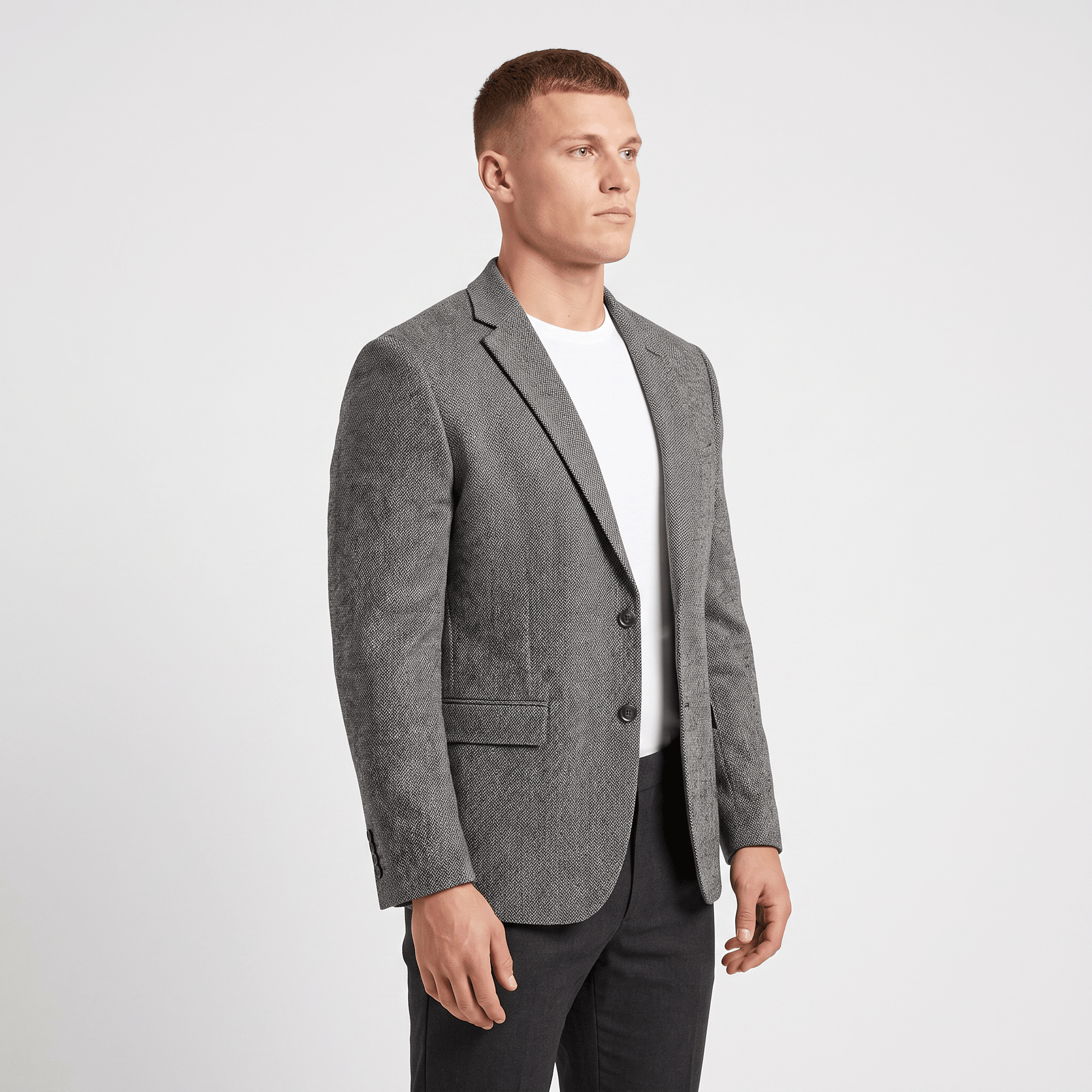 Side view of a man wearing a gray tweed blazer with a notched lapel and tailored silhouette.