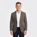 Man wearing a gray tweed blazer with a notched lapel, two-button closure, flap pockets, and tailored fit over a white dress shirt and navy trousers.
