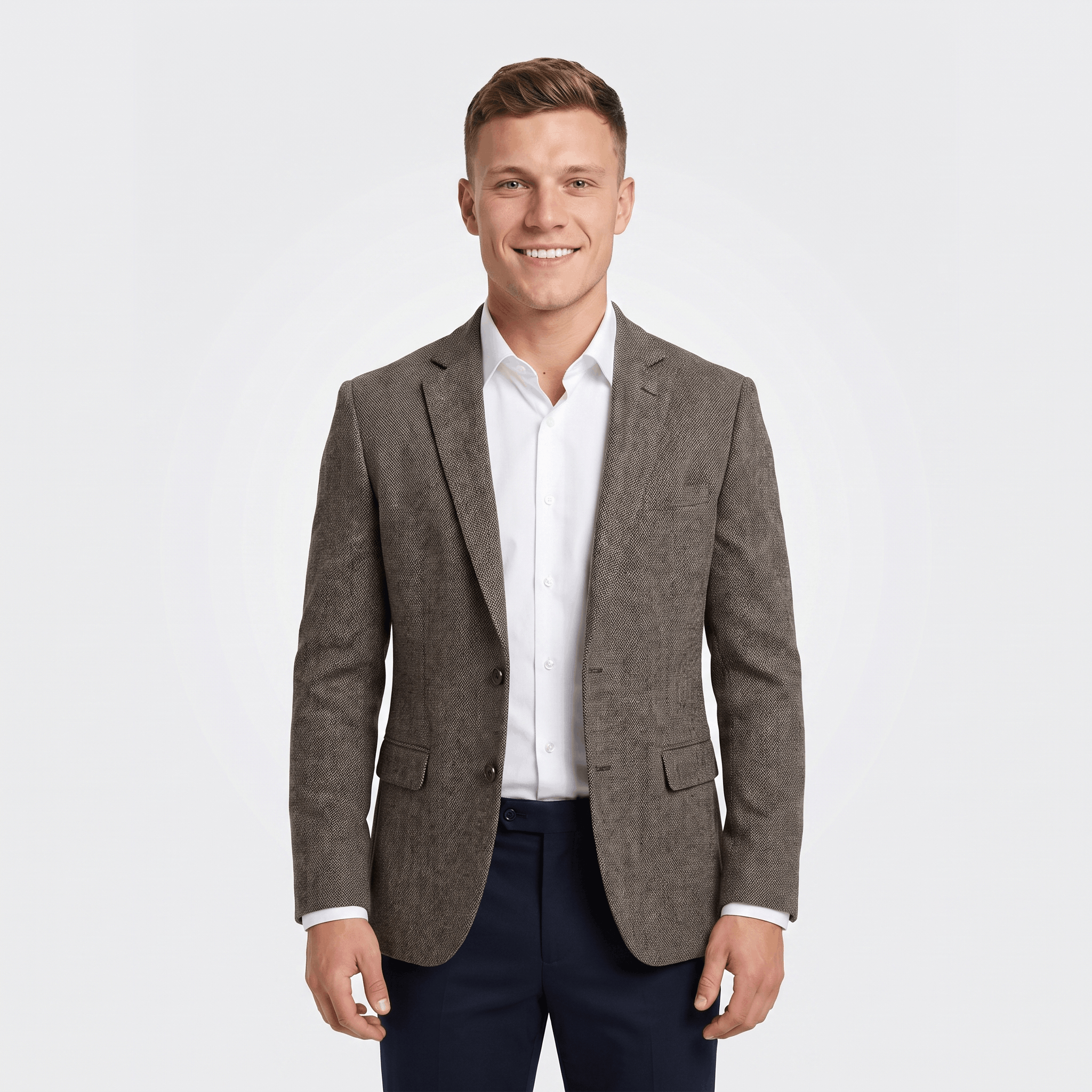 Man wearing a gray tweed blazer with a notched lapel, two-button closure, flap pockets, and tailored fit over a white dress shirt and navy trousers.