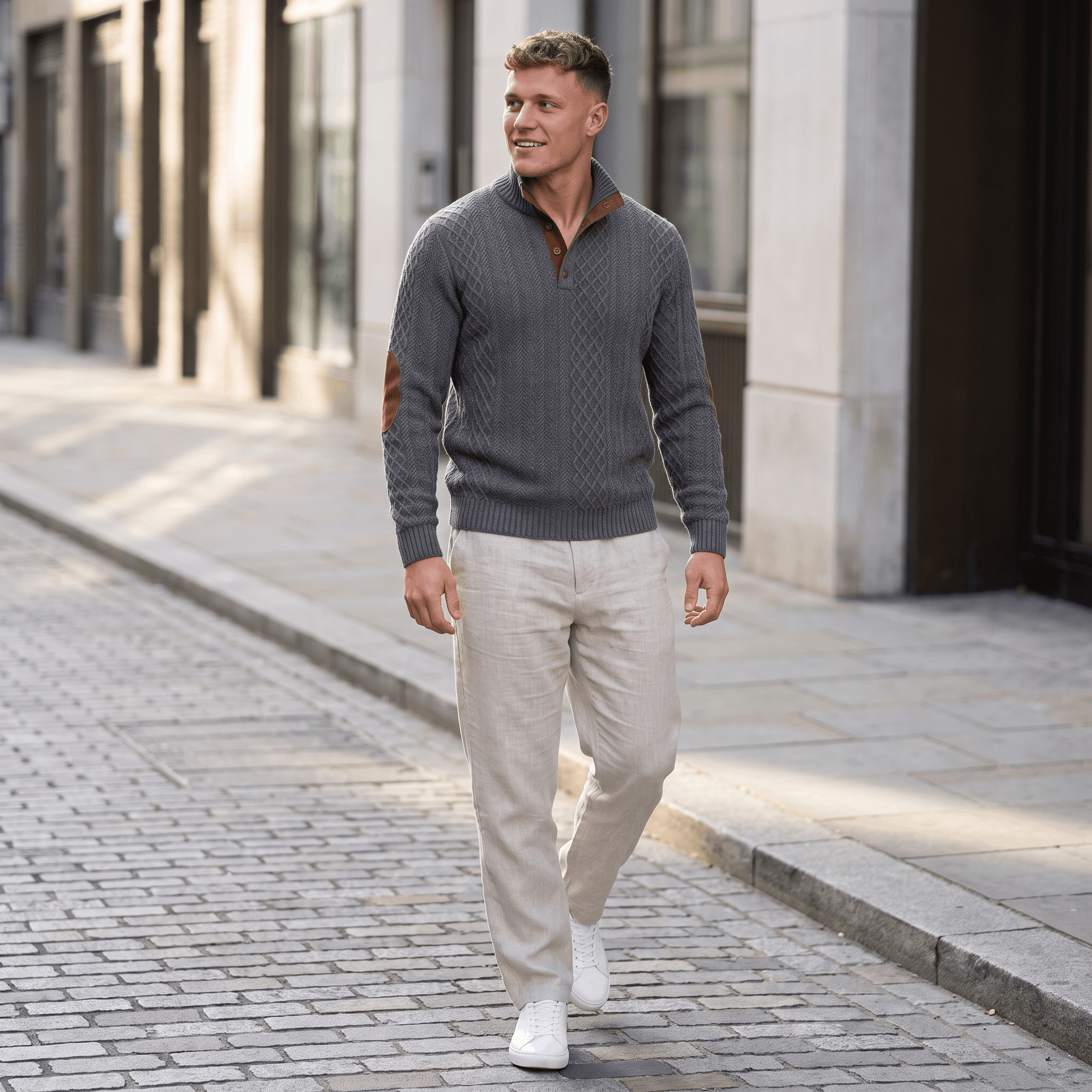 Man wearing a gray cable knit Henley sweater paired with light-colored trousers while walking in an urban setting.
