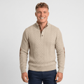 Man wearing a cream cable knit Henley sweater with a stand collar, button placket, faux suede elbow patches, and a classic fit.