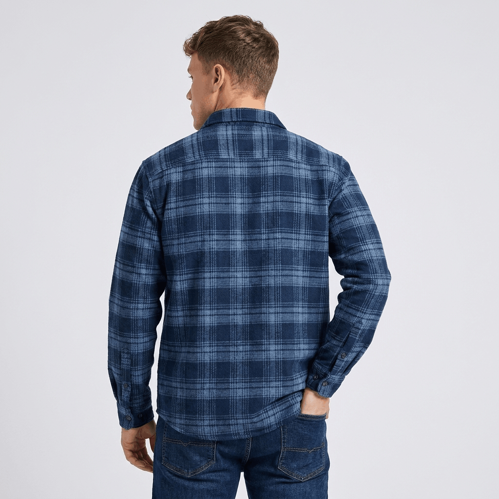 Back view of a man wearing a navy blue plaid overshirt jacket with a relaxed fit and long sleeves.